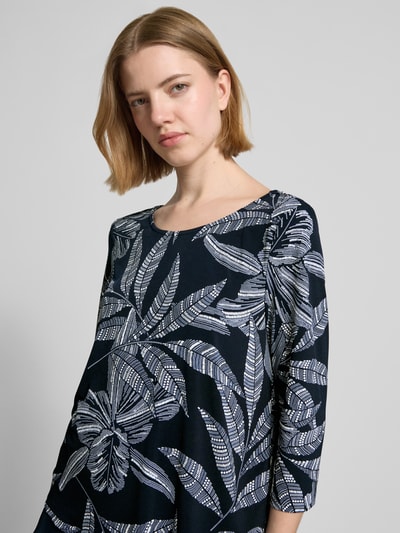 Frauenmodel trägt Blusenshirt mit rückseitigem Schlüsselloch-Ausschnitt von Vera Mont in Dunkelblau mit Blattmuster, Material-Mix, Nahaufnahme Oberkörper.
