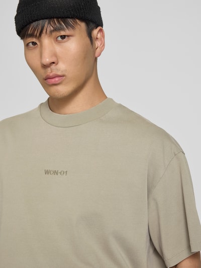 Männermodel trägt Relaxed Fit T-Shirt mit Logo-Stitching von WON HUNDRED aus reiner Baumwolle in Beige, Nahaufnahme Oberkörper.