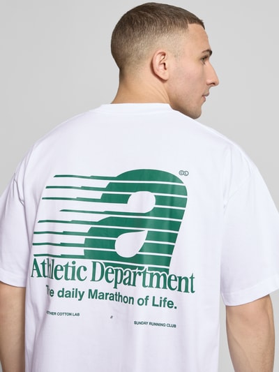Mężczyzna nosi t-shirt z nadrukiem z napisem Athletic Department od ANOTHER COTTON LAB, biała bawełna, prosty krój, długość tyłu 69 cm w rozmiarze M, model 'Athletic Department', okrągły dekolt, zdjęcie całych pleców