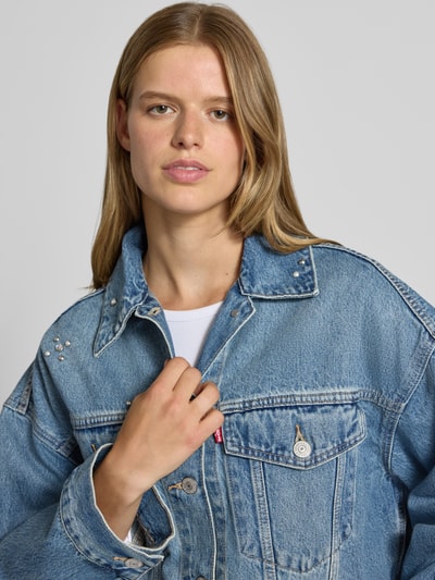 Frauenmodel trägt Loose Fit Jeansjacke aus reiner Baumwolle Modell 'LOOSE CROP TRUCKER' von Levi's® 300 in hellem Blau, grobe Struktur, Nahaufnahme Oberkörper.