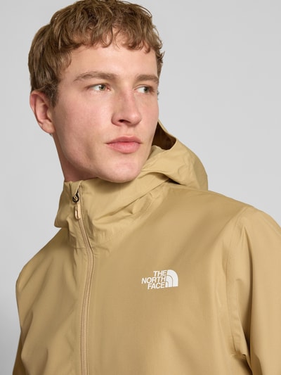 Männermodel trägt Jacke mit Kapuze von The North Face in Beige, Regular Fit, Label-Print, glatte Textur, Nahaufnahme Oberkörper.