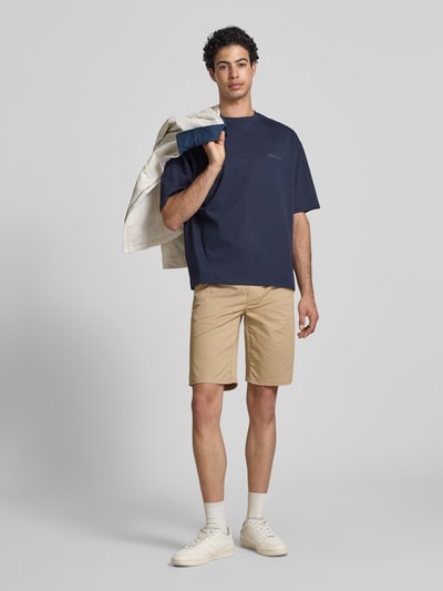Männermodel trägt Regular Fit Shorts mit elastischem Bund Modell 'MARCO' von Blend aus Baumwoll-Elasthan-Mix in Beige, Ganzkörperansicht von vorne. Shorts für Herren, Bundweite bei Größe M 39 cm, Innenbeinlänge 27 cm.