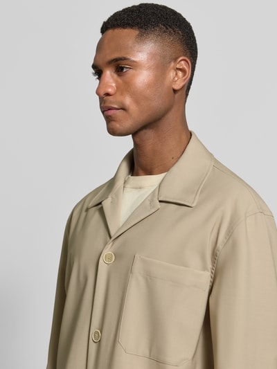 Männermodel trägt Hemdjacke aus Schurwoll-Elasthan-Mix mit Brusttasche von CRUNA in Beige, strukturierte Optik, Nahaufnahme Oberkörper.