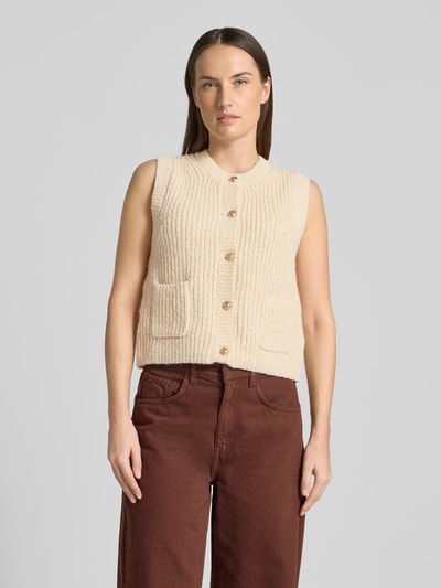 Frauenmodel trägt Strickweste Melange Effekt mit Schmuckknopf von Christian Berg Woman, beige Baumwoll-Mix, gerippte Struktur, Eingrifftaschen, Knopfleiste, Ganzkörperansicht von vorne.