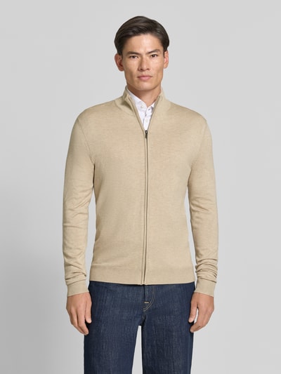 Męski model nosi Slim Fit Strickjacke aus Viskose-Mix mit Stehkragen von MCNEAL, kolor beżowy, faktura gładka, zamek błyskawiczny, elastyczne wykończenia, Długość tyłu w rozmiarze M: 70 cm, Długość rękawów w rozmiarze M: 70 cm, Ganzkörperansicht von vorne.
