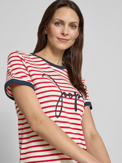 Frauenmodel trägt T-Shirt mit Label-Stitching Modell 'Trinity' von JOOP! in Rot-Weiß gestreift, reine Baumwolle, Nahaufnahme Oberkörper.
