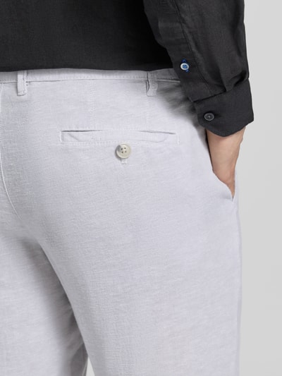 Mężczyznа nosi spodnie 'Hose aus Leinen-Viskose-Mix mit Eingrifftaschen' od Christian Berg Men, mieszanka lnu i wiskozy, krój regular fit, wpuszczane kieszenie, zapięcie na guzik i zamek błyskawiczny, szerokość w rozmiarze 50: 47 cm, długość wewnętrzna nogawki w rozmiarze 50: 78 cm, jasnoszary materiał, struktura lekko fakturowana, detal z tyłu, zbliżenie tylnej części.