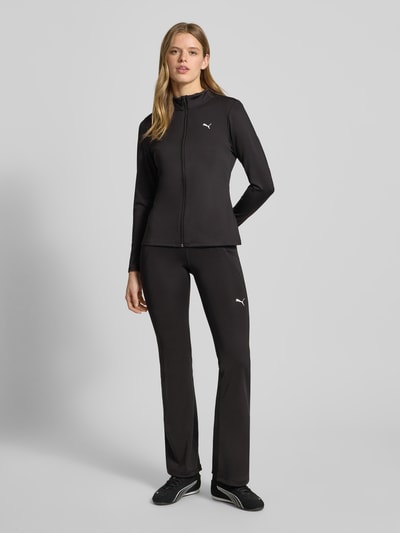 Kobiece modelka nosi Jacke mit Stehkragen od PUMA w kolorze czarnym, materiał-mix ze stretch, Slim Fit, widoczne logo, widok całej sylwetki z przodu.