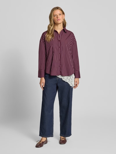 Modelka damska ma na sobie Regular Fit Hemdbluse mit Baumwoll-Anteil Modell 'OREGON' od ONLY w bordowe paski, ciemne jeansy, brązowe buty, widoczna biała koronka, kontekst: damska koszula ONLY, widok całej sylwetki z przodu.