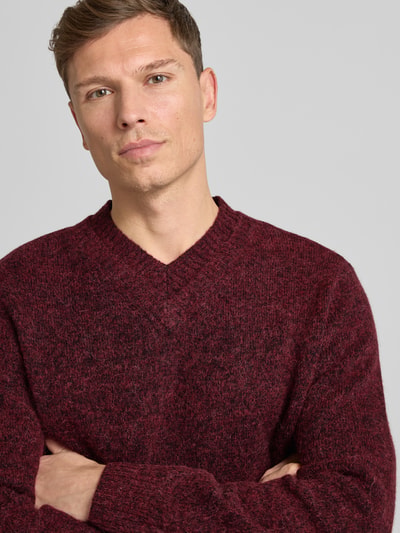 Männermodel trägt Strickpullover mit V-Ausschnitt Modell 'FLOYD' von Samsøe Samsøe in Bordeaux, Woll-Mix mit Alpaka, Nahaufnahme Oberkörper.