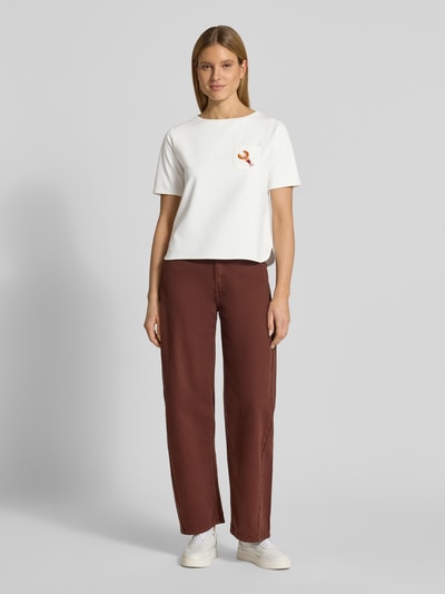 Frauenmodel trägt Damen T-Shirt mit Brusttasche und Motiv von More & More, Viskose-Mix mit Stretch-Anteil, Regular-Fit, Rundhalsausschnitt, Perlen, Rückenlänge bei Größe 36: 54 cm, Weiß mit farbigem Detail, Ganzkörperansicht von vorne.