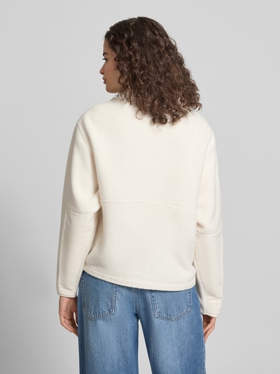 Frauenmodel trägt Fleecejacke mit Stehkragen und Label-Stitching von The North Face in Creme, Regular-Fit, Rückenansicht, Kontext: Damen Fleecejacke von The North Face, Stehkragen, Reißverschluss, Label-Stitching, Brusttasche mit Reißverschluss, Rückenlänge bei Größe S: 57 cm, Schulterbreite: 50 cm, Brustweite: 56 cm, Ärmellänge: 56 cm.