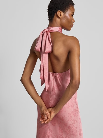Frauenmodel trägt Abendkleid mit Neckholder Modell 'Fiona' von Neo Noir in Satin, Maxilänge, taillierte Passform, Stehkragen, florale Struktur, Rosa, Detailaufnahme Rückenansicht.