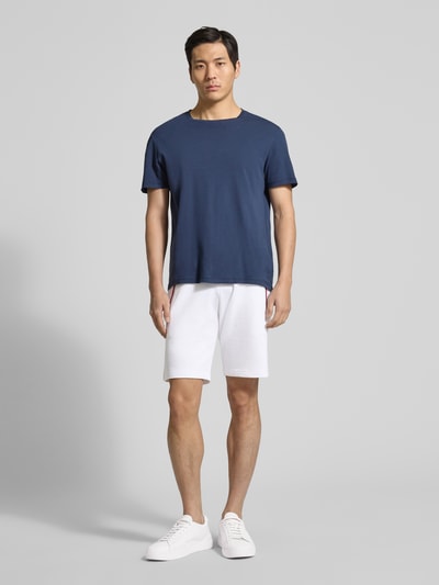 Männermodel trägt Shorts mit elastischem Bund von Christian Berg Men aus Baumwoll-Elasthan-Mix, Regular-Fit, Ganzkörperansicht von vorne. Eingrifftaschen mit Kontraststreifen, Tunnelzug, Bundweite bei Größe M 43 cm, Innenbeinlänge bei Größe M 23 cm.