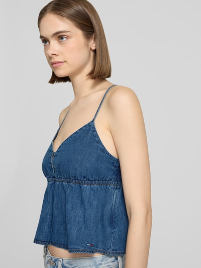 Frauenmodel trägt Denim Blusentop aus reiner Baumwolle von Tommy Jeans in mittlerem Blau mit V-Ausschnitt und verstellbaren Spaghettiträgern, körpernahe Passform, cropped Länge, Nahaufnahme Oberkörper.