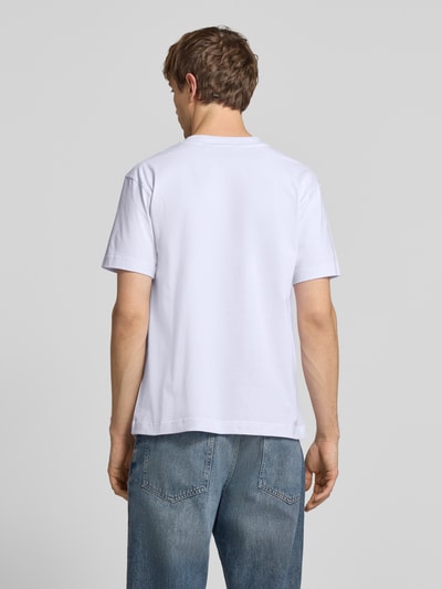 Męski model nosi T-shirt z wyhaftowanym logo model 'ACCIANO CLASSIC' od Ellesse z czystej bawełny, prosty krój, stójka, długość tyłu w rozmiarze M: 67 cm, kolor biały, gładka tekstura, całkowity widok z tyłu.