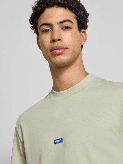 Männermodel trägt Regular Fit T-Shirt aus reiner Baumwolle Modell 'NIEROS' von Hugo Blue in Unifarbe mit Label Patch, Nahaufnahme Oberkörper.