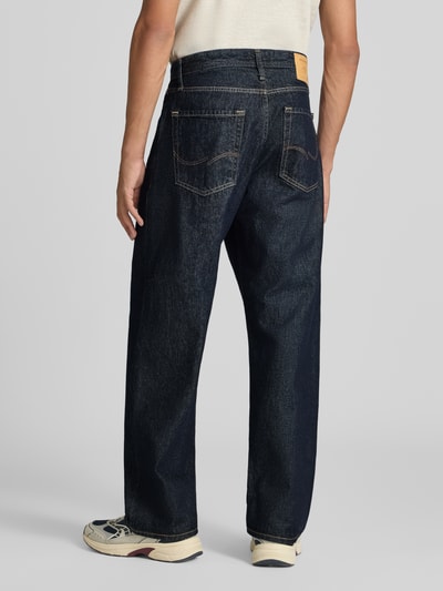 Männermodel trägt Wide Fit Jeans aus reiner Baumwolle Modell 'Alex' von JACK & JONES, dunkelblau, 5-Pocket, Ganzkörperansicht Rückansicht, Herren Jeans, Gürtelschlaufen, Knopf- und Reißverschluss, Bundweite 42 cm, Innenbeinlänge 76 cm.