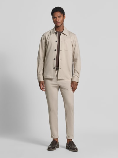 Männermodel trägt Slim Fit Stoffhose mit umgeschlagenen Hosenbeinen von Lindbergh in Beige, elastischer Material-Mix, Ganzkörperansicht von vorne.