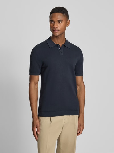 Männermodel trägt Slim Fit Poloshirt Modell 'Triton' von Drykorn aus Reine Baumwolle, Polokragen, Strukturmuster, Ganzkörperansicht von vorne.
