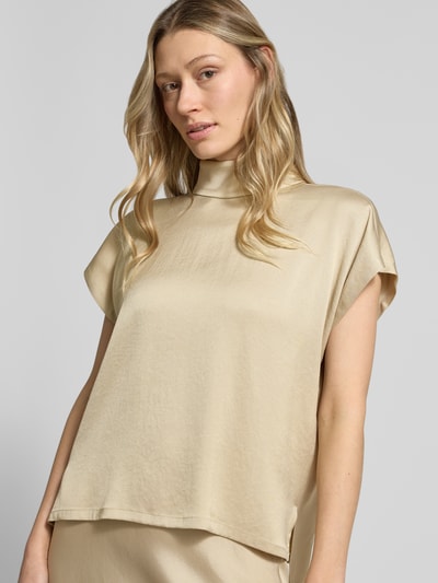 Frauenmodel trägt Blusenshirt mit Stehkragen Modell 'ALARIA' von Drykorn, beiger Farbton, glatte Textur, Regular Fit, Nahaufnahme Oberkörper.