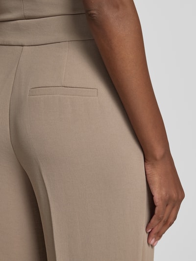 Frauenmodel trägt Straight Fit Hose mit Bügelfalten Modell 'Dani' von Forever New in Beige, glatte Textur, Detailaufnahme Rückansicht.