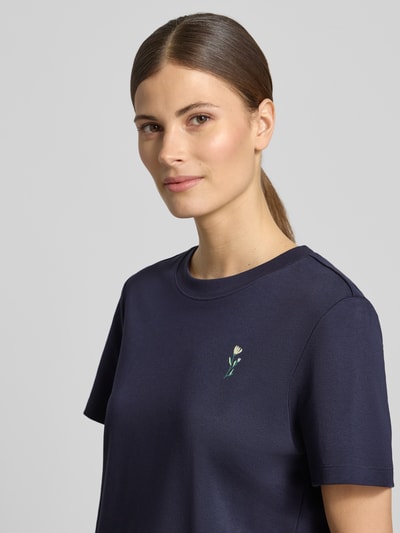Vrouwenmodel draagt Regular Fit T-Shirt aus reiner Baumwolle van s.Oliver RED LABEL in donkerblauw, korte mouwen, ronde hals, cropped lengte, motiefprint en labelapplicatie, jersey van puur katoen, Nahaufnahme bovenlichaam.