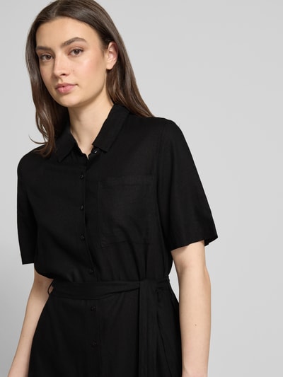 Modelka kobieca nosi czarne, jednokolorowe, midi Figurumspielendes Freizeitkleid aus Viskose-Leinen-Mix Modell 'PIA' od Pieces z krótkim rękawem i kieszenią na piersi, tekstura flammgarn, dekolt w serek, widok z przodu, zbliżenie na górną część ciała.