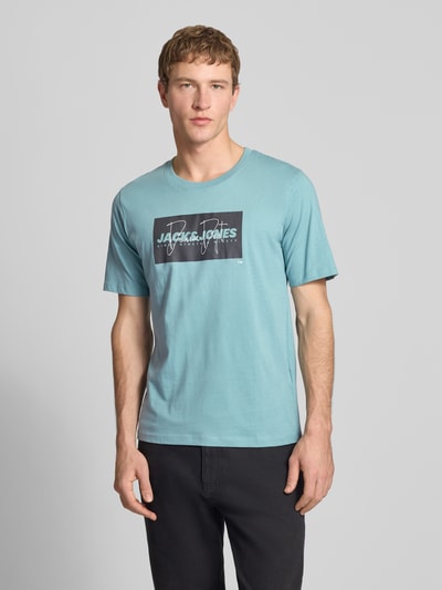Männermodel trägt Regular Fit T-Shirt aus reiner Baumwolle Modell 'COLE' von Jack & Jones in Blau mit Label-Print, Nahaufnahme Oberkörper.