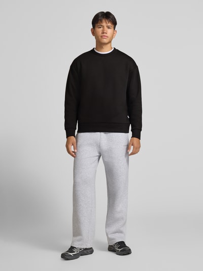 Männermodel trägt Regular Fit Sweatshirt mit Baumwoll-Anteil von JACK & JONES in Schwarz, Rundhalsausschnitt, Ganzkörperansicht von vorne.