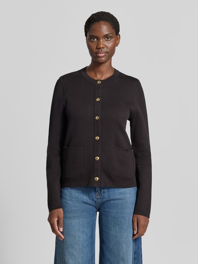 Frauenmodel trägt Regular Fit Strickjacke aus Baumwoll-Mix von Tommy Hilfiger in Schwarz mit goldfarbenen Knöpfen und aufgesetzten Taschen, Ganzkörperansicht von vorne, Damen Strickjacke von Tommy Hilfiger.