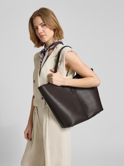 Frauenmodel trägt Shopper mit Label-Applikation Modell 'ANETT' von BOSS aus unifarbenem Glattleder mit strukturierter Oberfläche, Ganzkörperansicht von vorne.