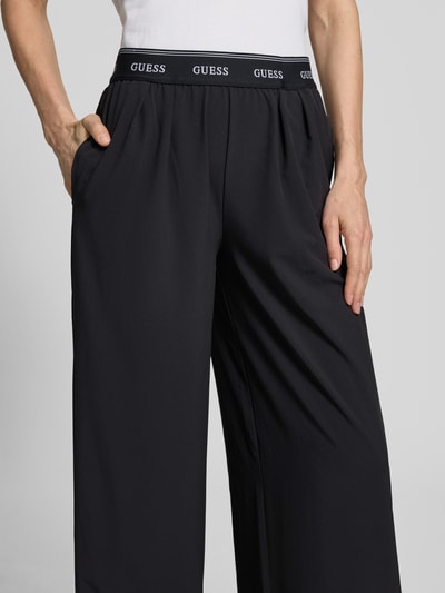 Frauenmodel trägt Wide Fit Pants mit elastischem Bund Modell 'SELENE' von Guess Activewear in Schwarz, Material-Mix, Nahaufnahme Oberkörper.