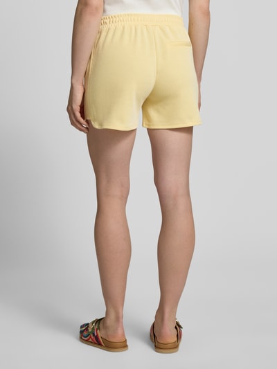 Frauenmodel trägt Shorts mit elastischem Bund Modell 'KATE PIQUE' von ICHI aus Baumwoll-Mix in Gelb, Regular-Fit, Ganzkörperansicht Rückansicht.