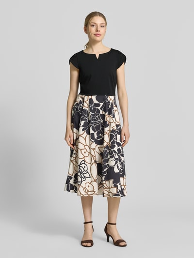 Frauenmodel trägt Midikleid im 2-in-1-Look von Betty Barclay in Schwarz mit geblümtem A-Linien-Rock aus Baumwolle, Ganzkörperansicht von vorne.