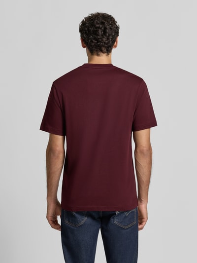 Männermodel trägt Regular Fit T-Shirt aus reiner Baumwolle von Lacoste in Dunkelrot, glatte Textur, Ganzkörperansicht Rückansicht.