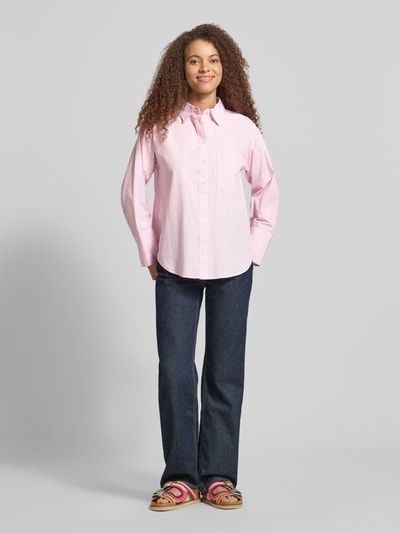 Frauenmodel trägt Regular Fit Bluse mit Brusttasche von Gina Tricot in Rosa, Reine Baumwolle, Hemdblusenkragen, Knopfleiste, Ganzkörperansicht von vorne.