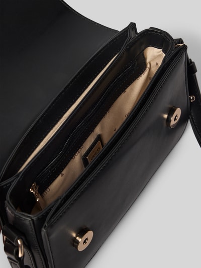 Produktfoto, Handtasche mit Label-Applikation Modell 'JANIE' von Guess, czarna skóra, złote zapięcia magnetyczne, wnętrze z beżową podszewką z logo, główna komora z zamknięciem magnetycznym, wewnętrzna kieszeń na zamek, regulowany pasek na ramię, Szerokość w rozmiarze 1: 21 cm, długość 13 cm, głębokość 6 cm, długość paska 78 cm