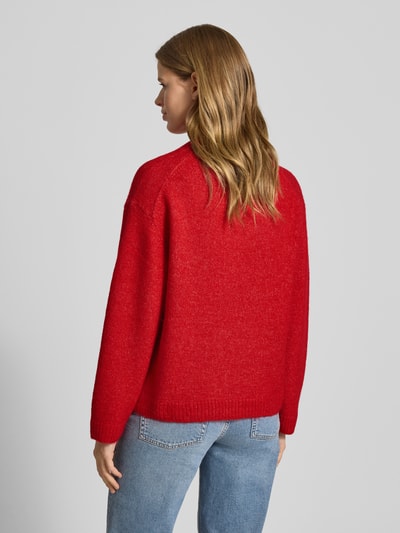 Vrouwenmodel draagt Strickpullover mit Woll-Anteil van Gina Tricot in rood, grof gebreid, losse pasvorm, ribboorden, rugaanzicht, helemaal.