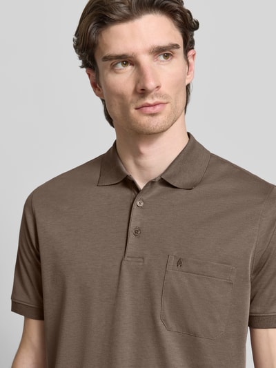 Mężczyznę model nosi Regular Fit Koszulka polo z brustaszą od RAGMAN, wykonana z bawełny, wyhaftowane logo, kolor brązowy, nahaufnahme oberkörper. Długość tyłu 62 cm przy rozmiarze M.