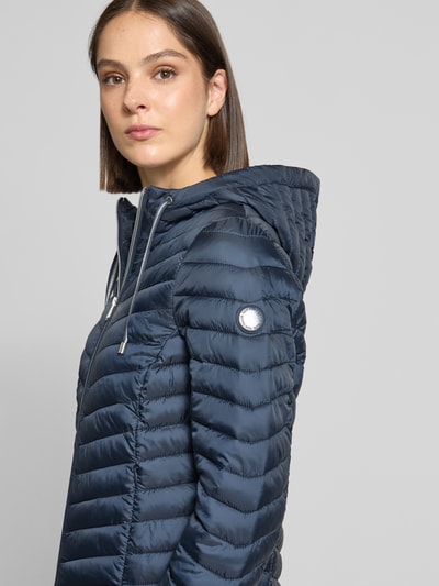 Frauenmodel trägt Regular Fit Steppjacke mit Kapuzenkragen von Tom Tailor in Dunkelblau mit silberfarbenem Zipper, Nahaufnahme Oberkörper, Damen Steppjacke von Tom Tailor.