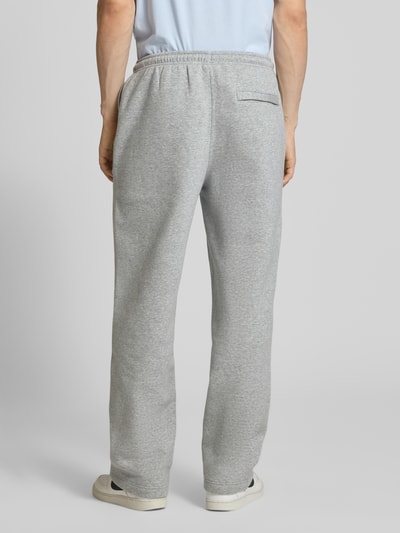 Männermodel trägt graue Sweatpants mit Logo-Stitching und Eingrifftaschen von Nike aus Baumwoll-Mix, Ganzkörperansicht Rückansicht.