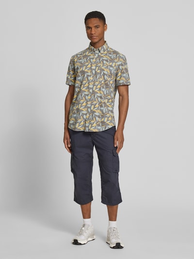 Männermodel trägt Regular Fit Freizeithemd mit Button-Down-Kragen von camel active, Allover-Look in Gelb und Grau, Ganzkörperansicht von vorne.