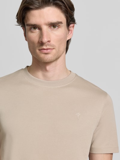 Männermodel trägt T-Shirt mit Label-Stitching Modell 'Priamo' von JOOP! Collection aus beigefarbener Baumwolle, Nahaufnahme Oberkörper.