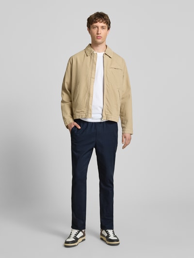 Männermodel trägt Tapered Leinenhose aus Baumwoll-Leinen-Mix Modell 'LINUS' von Only & Sons in Melange-Optik mit seitlichen Eingrifftaschen, Tunnelzug und elastischem Bundabschluss, Ganzkörperansicht von vorne.
