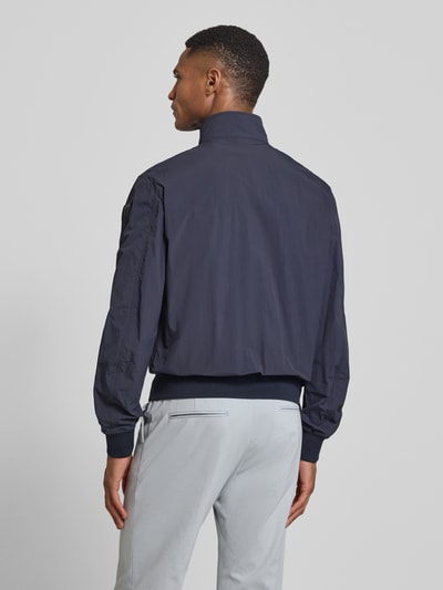 Męski model nosi Jacke mit Pattentaschen Modell 'Alwin' od Blauer Usa, ciemnogranatowy kolor, prosty krój, długi rękaw, widok całej sylwetki tyłem. Szerokość w rozmiarze M: 54 cm, długość tyłu: 66 cm, szerokość ramion: 47 cm, długość rękawa: 67 cm.