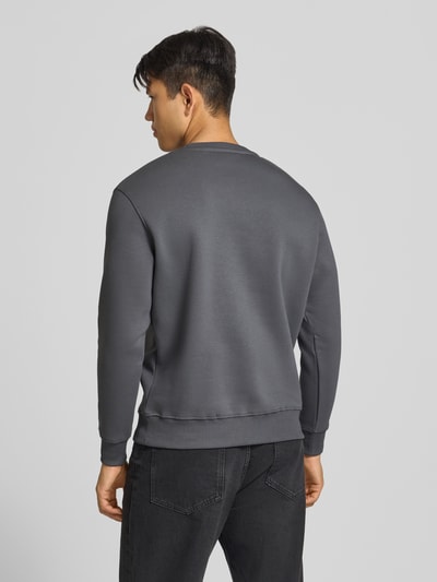 Männermodel trägt Regular Fit Sweatshirt aus Baumwoll-Mix mit Logo-Print von Alpha Industries, graue Farbe, gerippte Abschlüsse, Ganzkörperansicht Rückansicht.