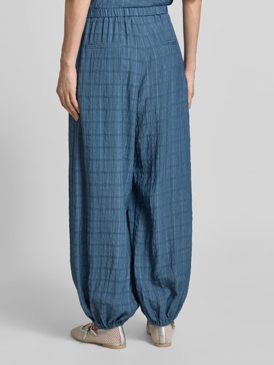 Frauenmodel trägt Stoffhose mit elastischem Bund von Jake*s Casual in Blau, lockerer Schnitt, sichtbare Gesäßtaschen, strukturierte Oberfläche, Ganzkörperansicht Rückansicht.