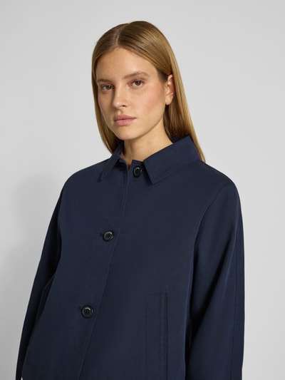 Vrouwenmodel draagt Regular Fit Trenchcoat aus Baumwoll-Lyocell-Mix van s.Oliver RED LABEL in effen donkerblauw twill, labelapplicatie, steekzakken, platte kraag, lange mouw, korte look, eenrijige knoopsluiting, mix van katoen en lyocell, detailopname bovenlichaam, vooraanzicht.