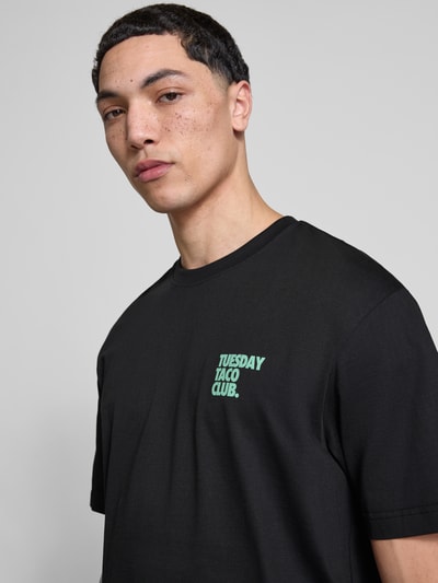 Mężczyznamodel nosi Relaxed Fit T-Shirt aus reiner Bio-Baumwolle Modell 'FRED' od Only & Sons, czarny, nadruk, krój relaxed fit, bawełna organiczna, uniseks, widok na górną część ciała z przodu